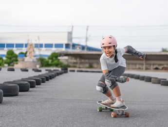 asian child skater or kid girl fun playing skateboard or smile riding carving surf skate on car tires track in skate park lane for extreme sports exercise and wears helmet knee guard for body safety