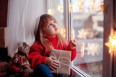 happy baby sitting on the window with christmas present