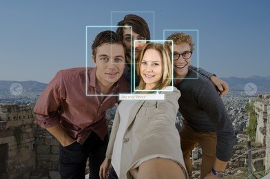 tagging and sharing a friend in a selfie of four people using facial recogintion software applications in front of a large city for sharing on varous social media platforms