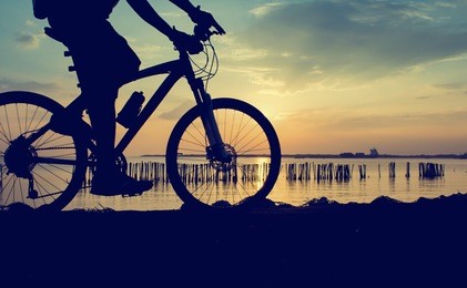 silhouette of the cyclist riding a road bike at sunset