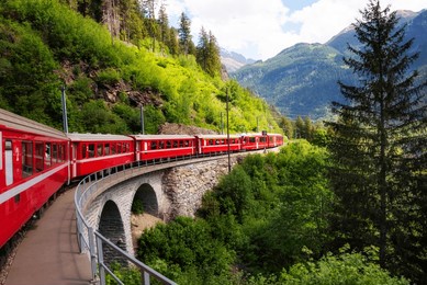 red train moving in beautiful mountain landscape in switzerland