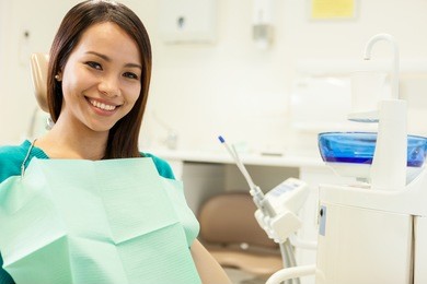photo of asian young woman sitting at the dentist while smiling towards the camera