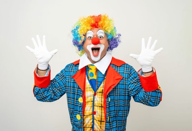 mr clown. portrait of funny shocked face comedian clown man in colorful costume wearing wig standing posing smiling to camera. happy expression amazed bozo in various pose on isolated background.