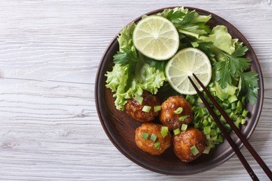 fish balls in curry sauce on a plate with fresh herbs. top view of a horizontal 