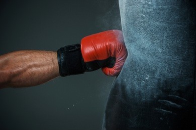 hand  of boxer and punching bag over black background