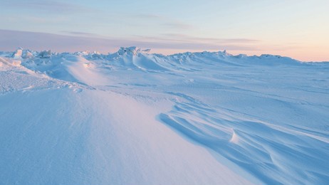 winter arctic landscape. cold frosty winter weather. harsh polar climate. ice hummocks on the frozen sea in the arctic. view of snow and ice at sunset. sastrugi. wind sculpted patterns on snow surface