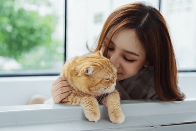 happy asian woman owner cute cat playful in a home. friendship of pet and human people lifestyle.