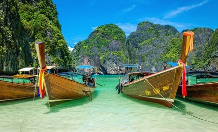 the famous heavenly beach maya bay on phi phi islands with colorful longtail boats and limestone hills in the background, thailand