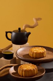 mid-autumn festival celebration with delightful mooncakes displayed on few round-shaped dishes. black teapot and teacup are arranged. happy mid autumn festival