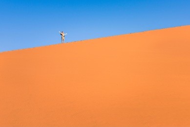 adventurous man lonely traveler hiking on sand dune at deadvlei near sossusvlei - namibian world famous desert - adventure trip concept to african nature wonder shooting travel photography