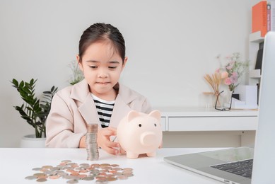 little girl wearing a cream suit analyzing coins concept of finance and investment in white room