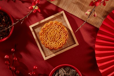 wooden tray in square-shaped containing a mooncake. red bowls of sunflower seeds and melon seeds displayed. people usually watch the full moon in the middle of autumn