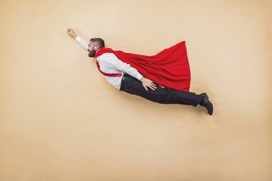 manager in a superman pose wearing a red cloak.
