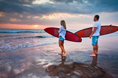 couple of surfers walking on coast in indonesia, bali, kuta