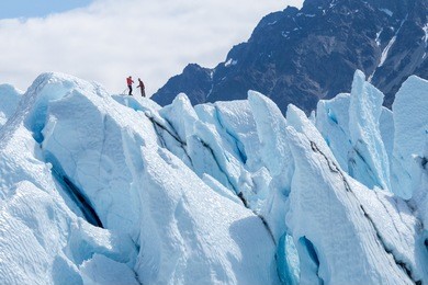 two climbers reached the top of glacier. challenging and hostile environment. several crevices around. matanuska glacier, alaska, usa / two climbers reached the top of glacier