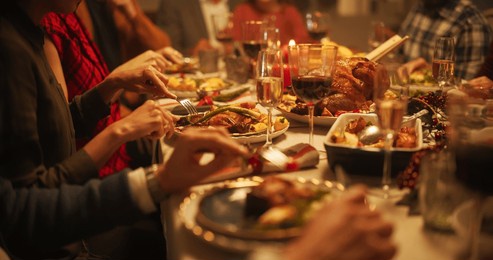 portrait of a diverse group of relatives and friends sitting together behind a dining table with tasty meals and festive decorations. guests telling funny stories, creating a joyful holiday mood