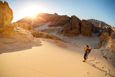 hiker walking on sand in the desert with valley on the background
