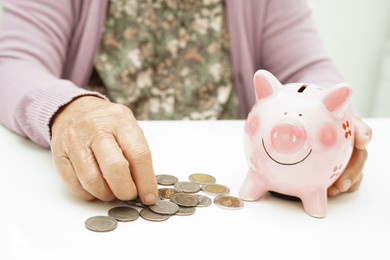retired elderly woman counting coins money with piggy bank and worry about monthly expenses and treatment fee payment.
