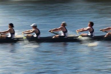 rowers in a rowing boat pulling in harmony, motion blurred to accent speed
