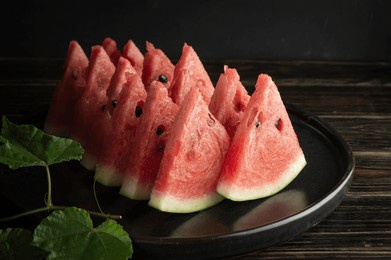 close-up of ripe, sweet and crisp red watermelons, deliciously thinly sliced, arranged in a black ceramic dish on an old wooden background.