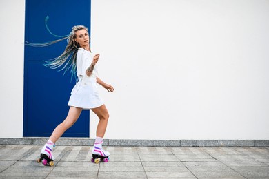 young woman practicing rollerskating against white wall. happy girl with rollerskates in the skating ground.healthy lifestyle. sport activity.