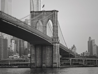 the brooklyn bridge in black and white with new york city in the background.