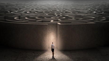 puzzled businesswoman standing near entrance of labyrinth