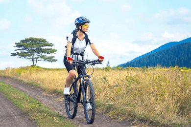 beautiful and happy woman cyclist rides a bicycle on the road in nature. healthy lifestyle and sports. leisure and hobbies