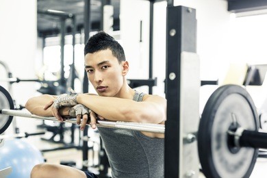 asian man doing crunch exercises in a gym.