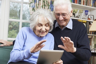senior couple using digital tablet for video call with family