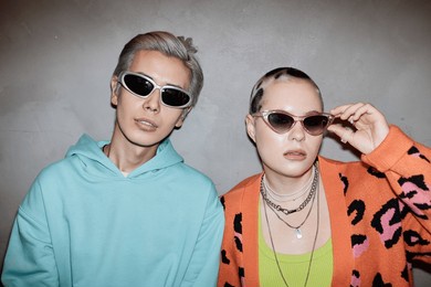 portrait of two creative young couple wearing sunglasses and posing with flash