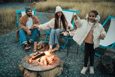 happy family roasting marshmallow sitting by the fire outdoors.