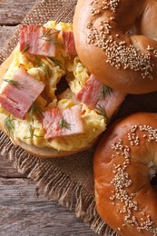 bagel with egg and bacon on an old wooden table close-up. vertical view from above 