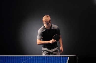 portrait of young man playing tennis on black background