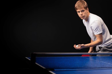 portrait of young man playing tennis on black background