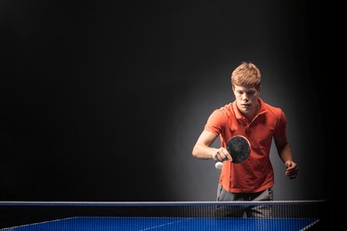 portrait of young man playing tennis on black background