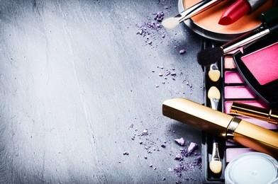 various makeup products on dark background with copyspace