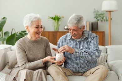 saving money investment for future. senior adult mature couple holding piggy bank putting money coin. old man woman counting saving money planning retirement budget. saving investment banking concept