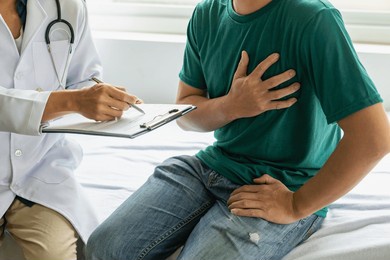 asian male heart patient comes to consult doctor. at the clinic to check the heart and lungs male doctor using a stethoscope listen to the patient's breathing or heartbeat.