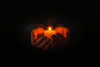 religion concept.concentration time.remembrance of the dead.burning candle in a mans hand on dark background.