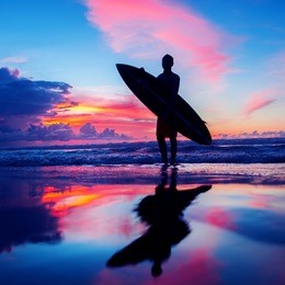 young surfer with board on the beach