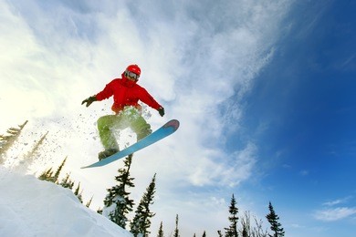 snowboarder jumping through air with deep blue sky in background