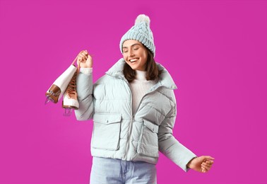 young woman in winter clothes with ice skates on purple background