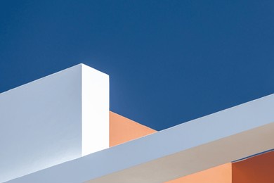 architecture background abstract geometric shapes. white and orange walls against a blue sky. modern concrete structure building detail. architectural construction. minimal design style. angular lines
