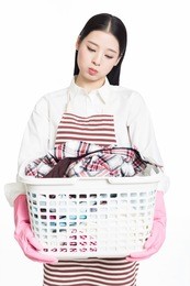 young woman holding a basket of folded laundry. white background.