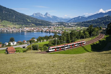 passenger train type stadler flirt of schweizerische bundesbahnen sbb railway at grosser mythen mountain at lake zug in the swiss alps in arth, switzerland