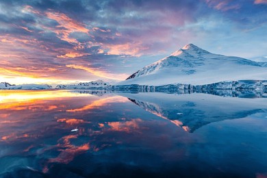 beautiful antarctica landscape, mountains next to the sea with breathtaking reflection during midnight sun, sunset and sunrise in once, in antarctica