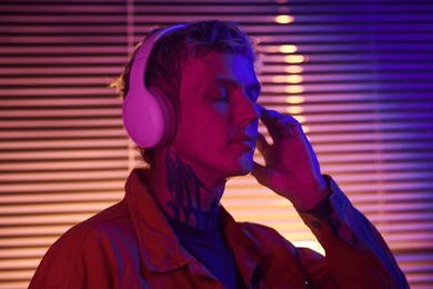 young man standing with eyes closed when listening to music track in headphones