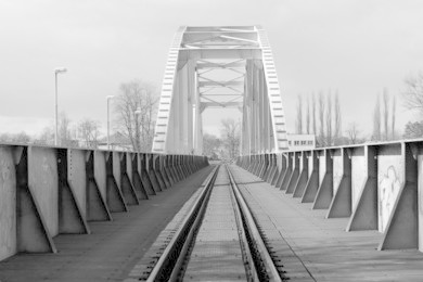 black and white photo of a metal bridge over the river