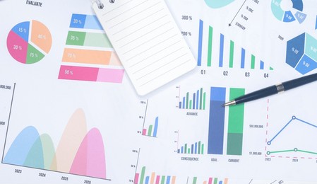 notepad and pen with business graphs finance document.